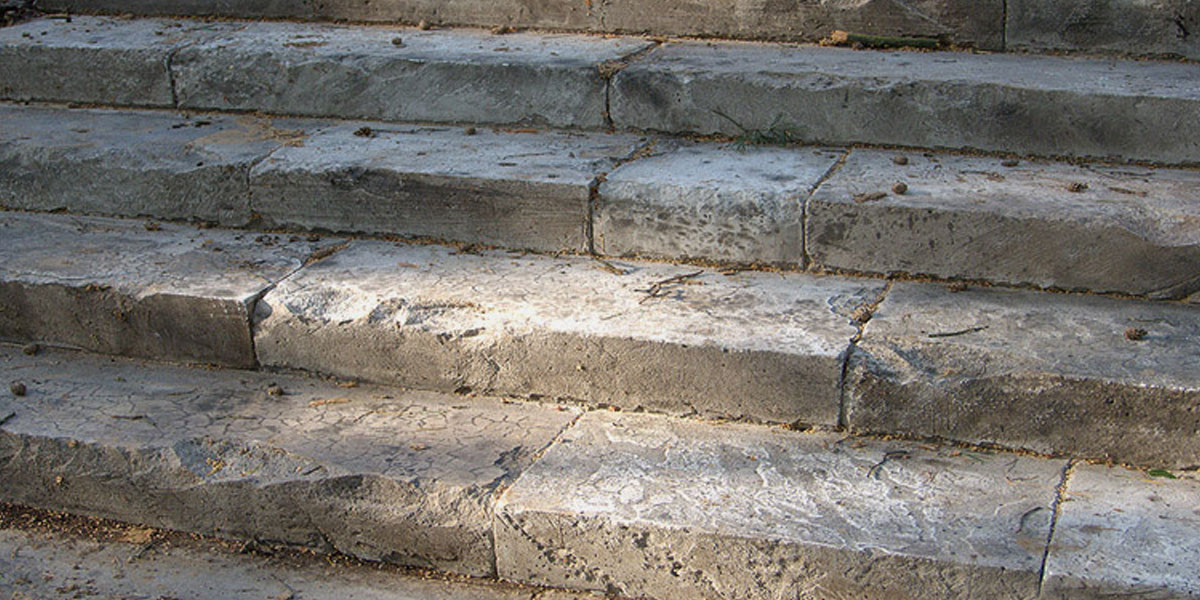 Ступеньки лестницы из природного камня с упавшими на них шишками